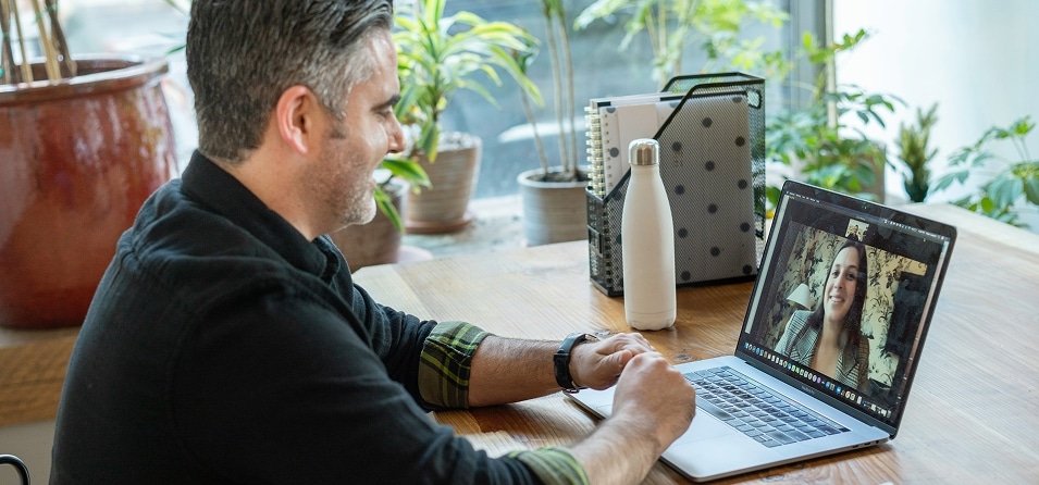 Ein Mann am Arbeitsplatz der über seinen Laptop eine online Beratung durchführt