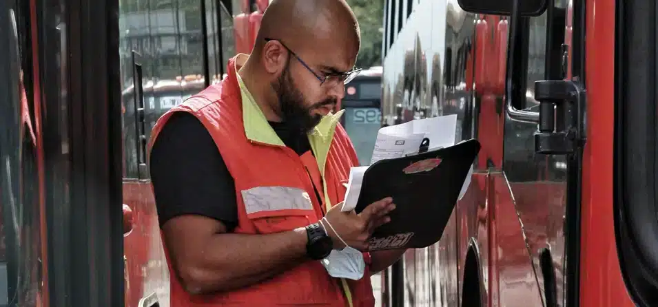 Ein Mann mit einem Klemmbrett zwischen zwei Bussen